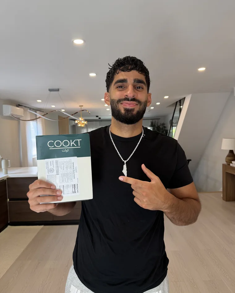 Moose holding a sealed COOKT halal meal in his kitchen