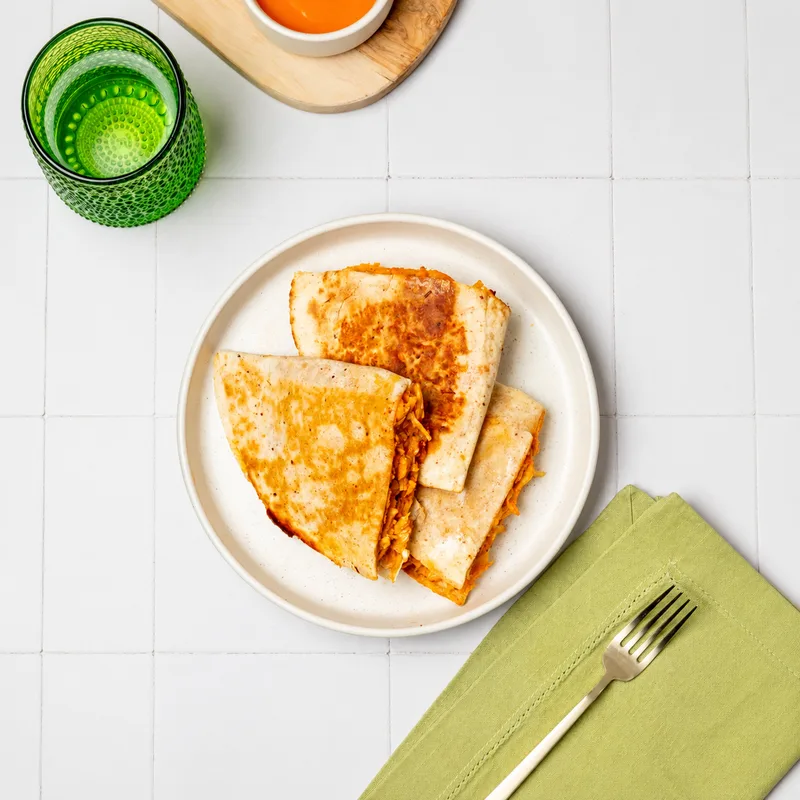 Buffalo Chicken Quesadilla wedges on a plate with dipping sauce