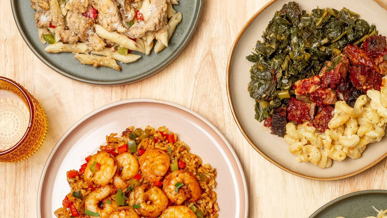 Six COOKT halal meals plated across a wooden table, from shrimp rice to brisket to alfredo